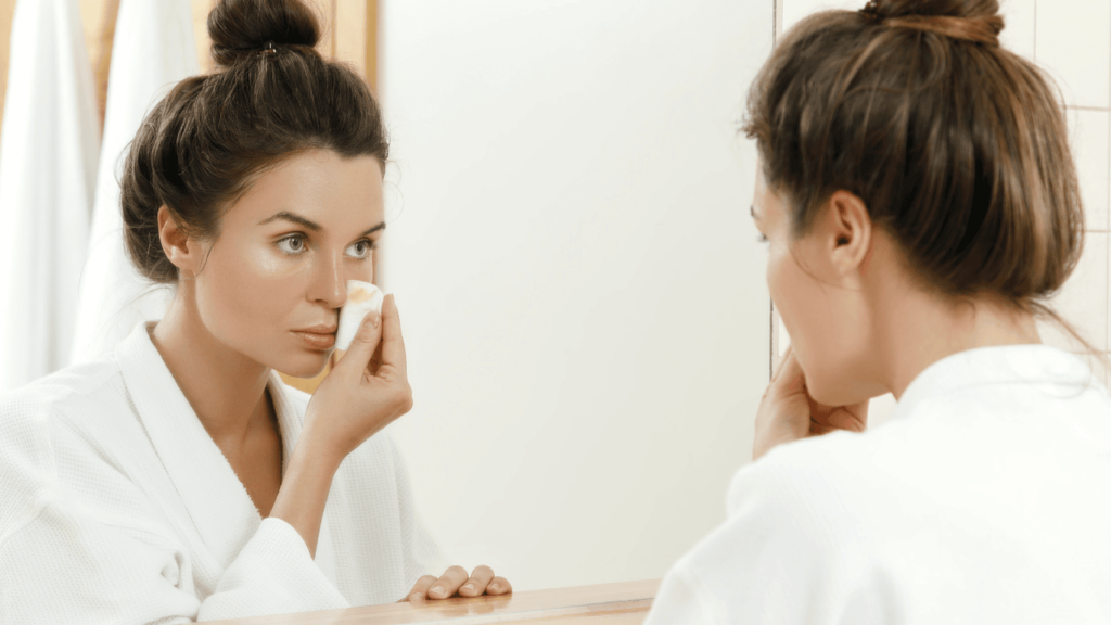 Mujer desmaquillándose frente a un espejo