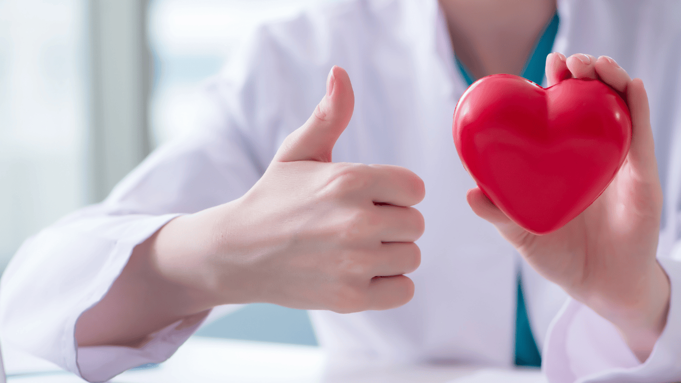 Mujer sosteniendo un corazón falso y poniendo el pulgar hacia arriba
